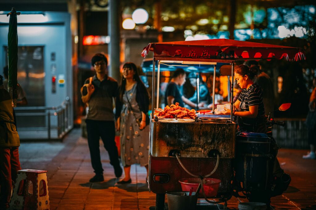 Street food stall on a Bangkok side street, woman cooking pad thai